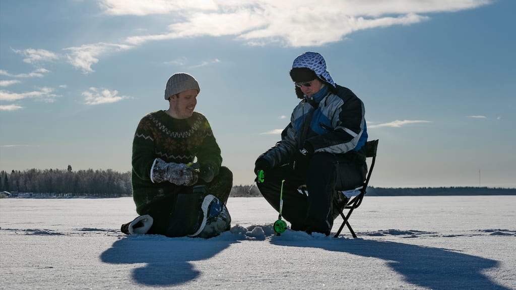 Two ice anglers at a hole on the snowy ice