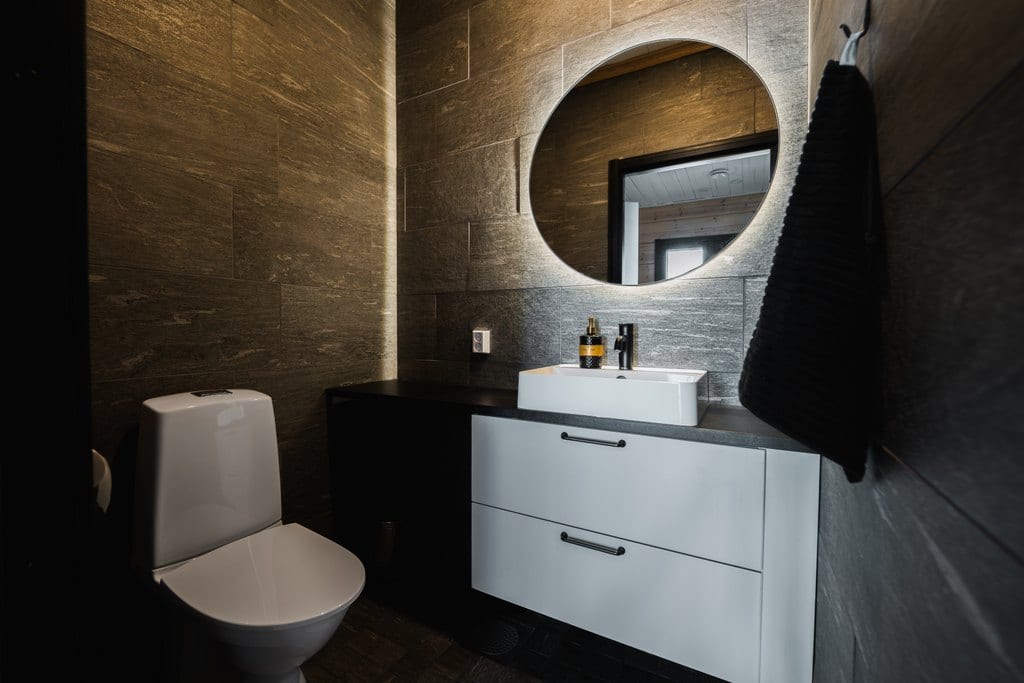 Bathroom with a white vanity and a lit round mirror