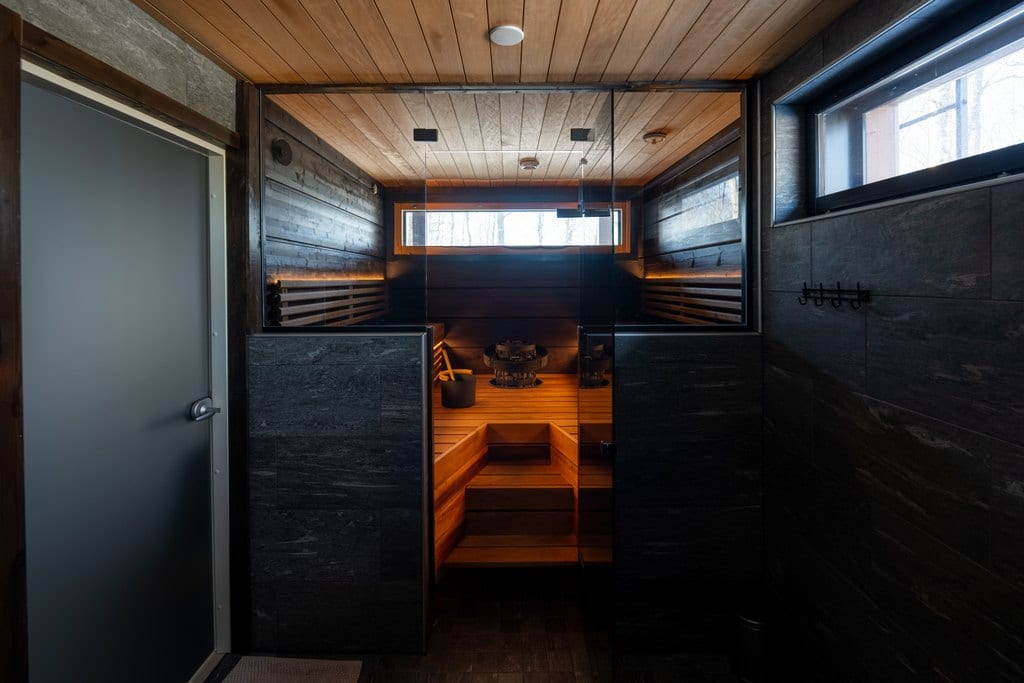 Sauna behind a glass wall and dark stone tiles in the washroom