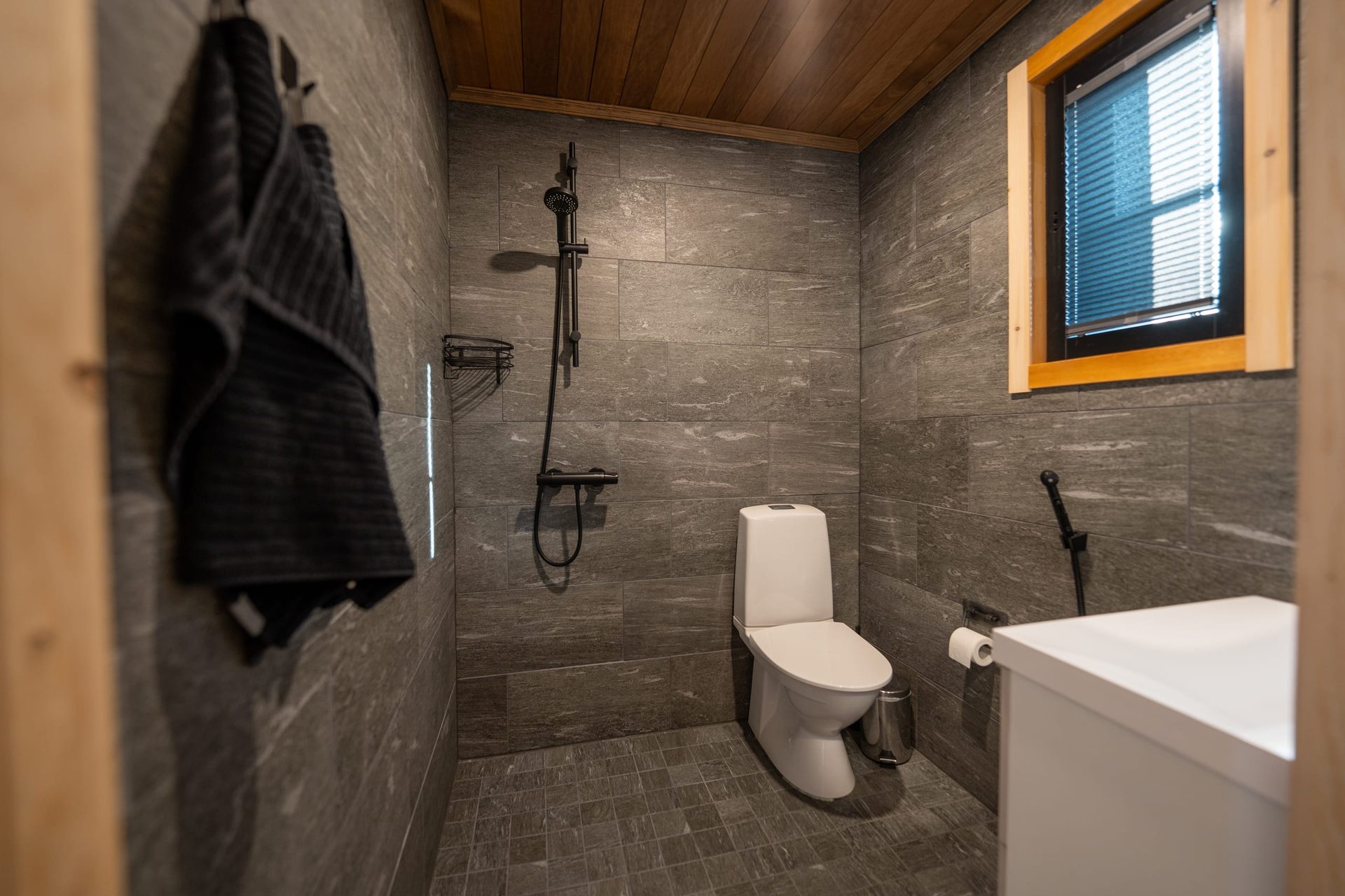 Uitto bathroom with gray tiles, shower and toilet