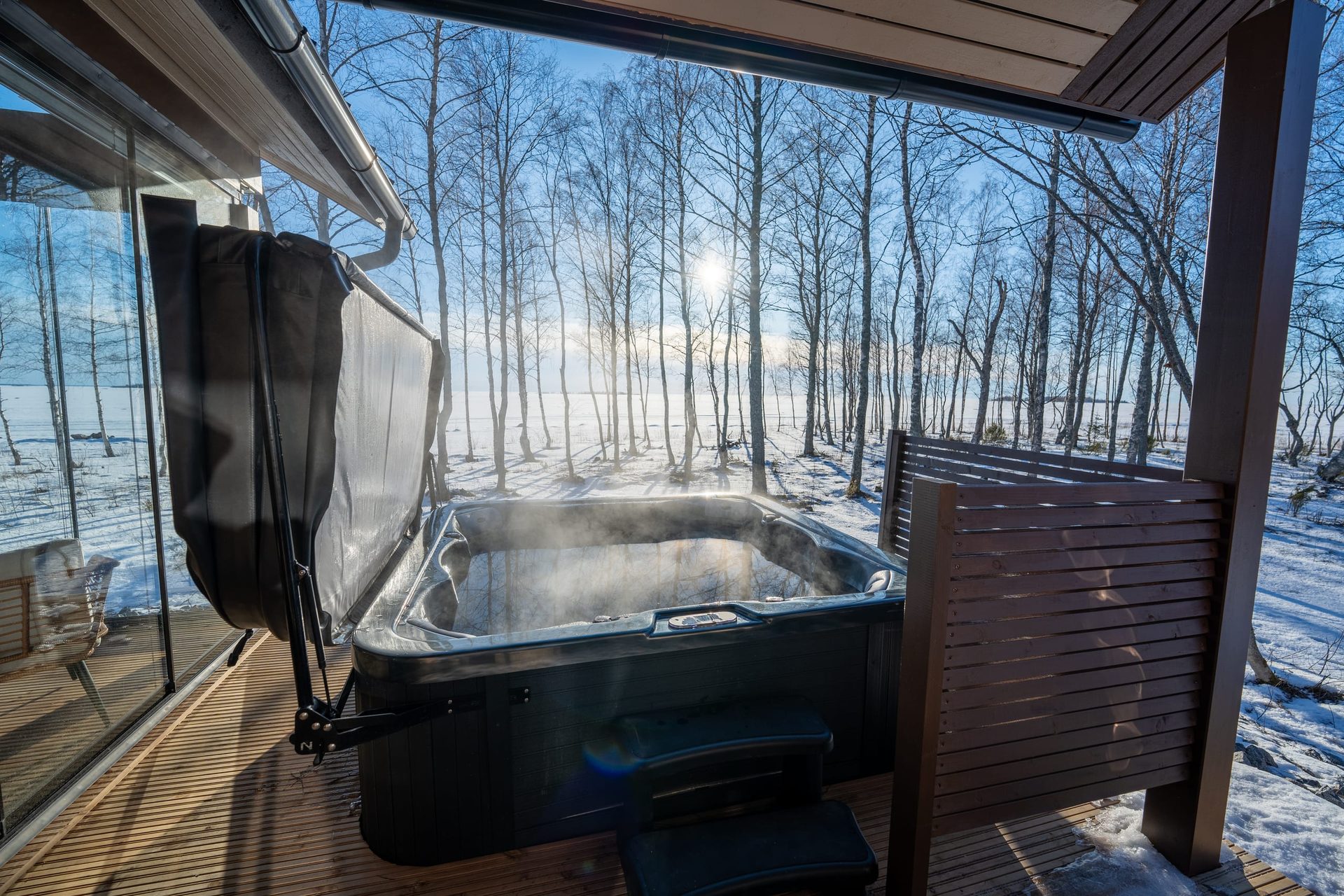 Usva's steaming hot tub on a covered deck in a snowy birch grove