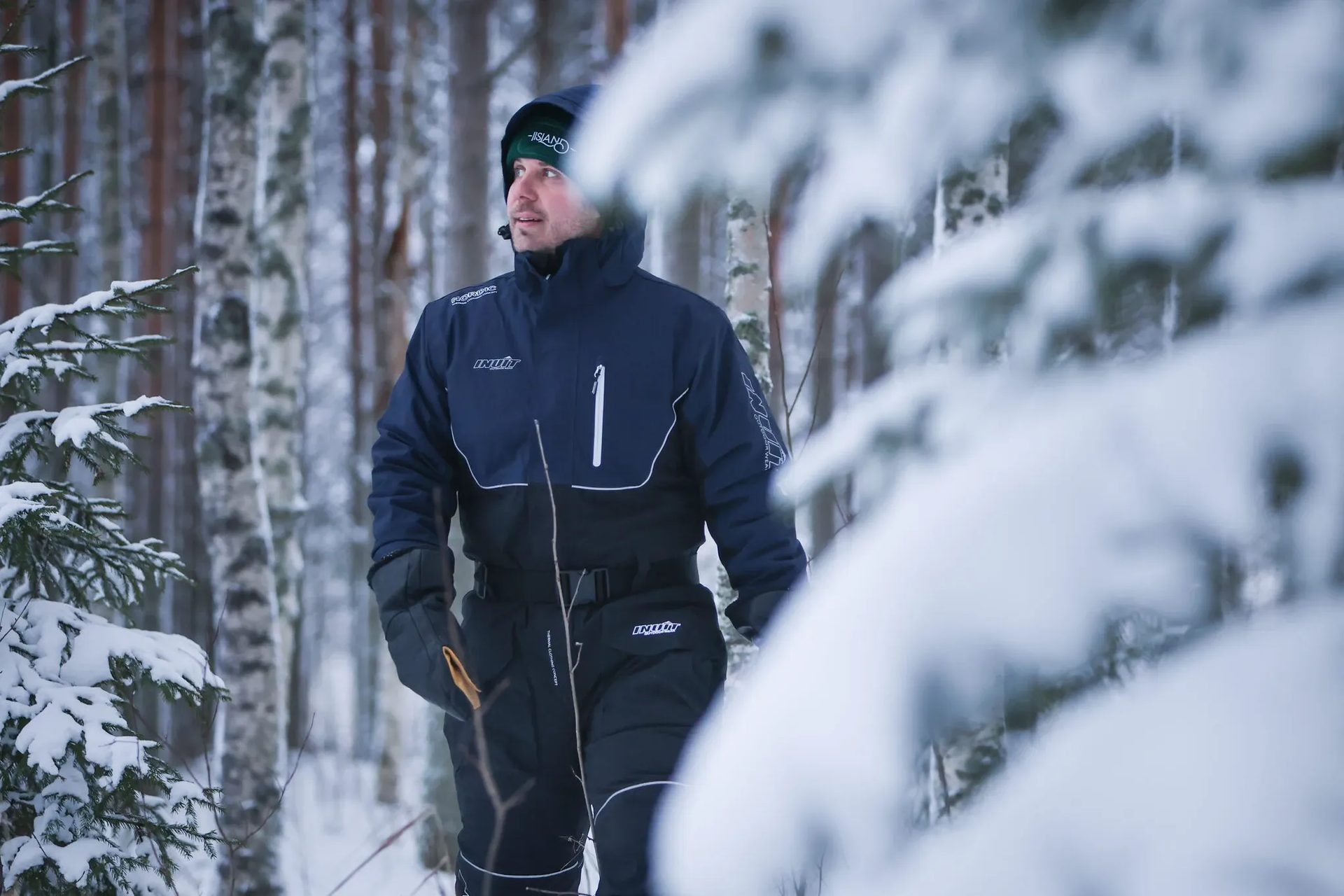 A man in a winter jumpsuit in a snowy forest