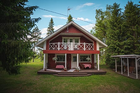 Uoman punainen kaksikerroksinen mökki ja nurmipiha kesällä