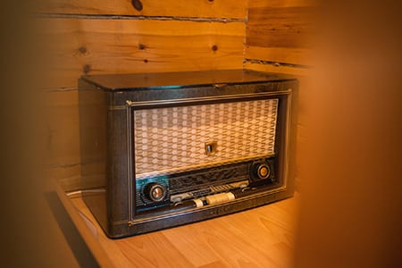 Vanha putkiradio Uoman hirsiseinän vieressä