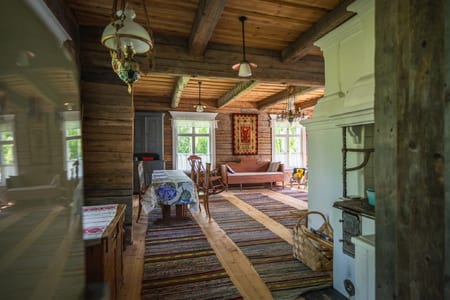 Pauhu log room with a dining table, rag rugs and chandeliers