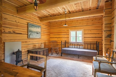 Pauhu log room with a daybed, rocking chair and cast-iron stove