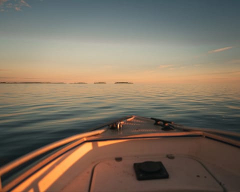 Veneen keula tyynellä merellä auringonlaskussa
