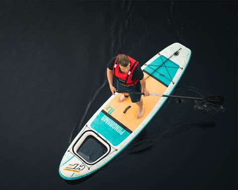 Man paddling a stand-up paddleboard in a life vest