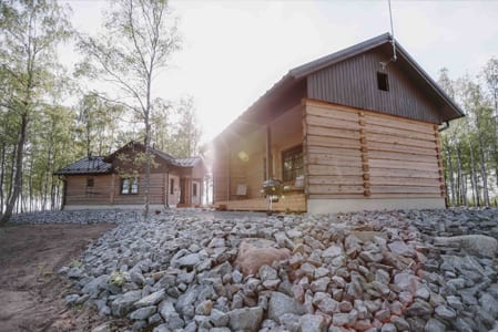 Log cabins in a birch grove with rocks in front