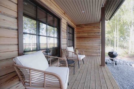 Uitto covered terrace with rattan chairs and a kettle grill